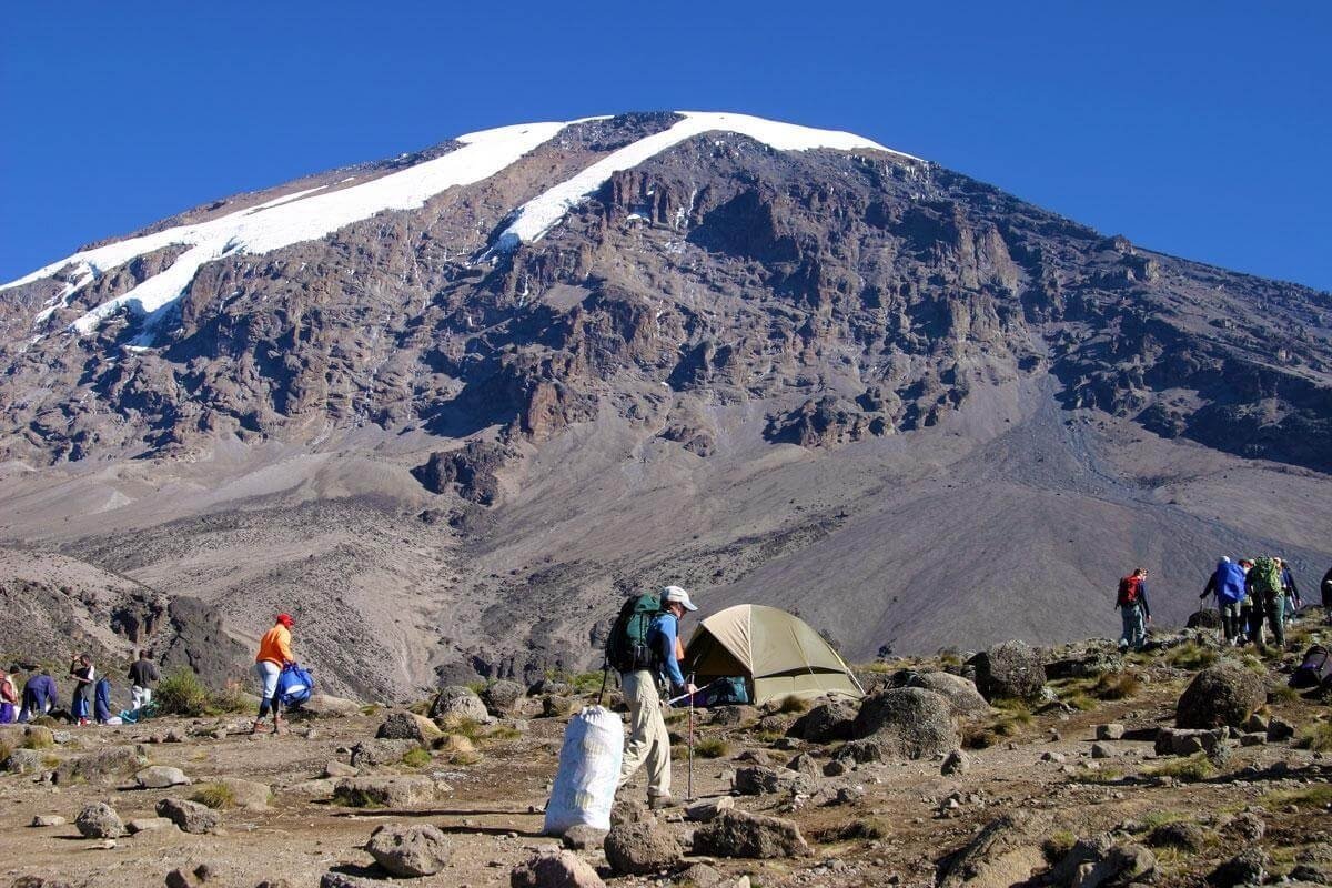 A trekker looking out over a vast green valley on the Kilimanjaro trail
